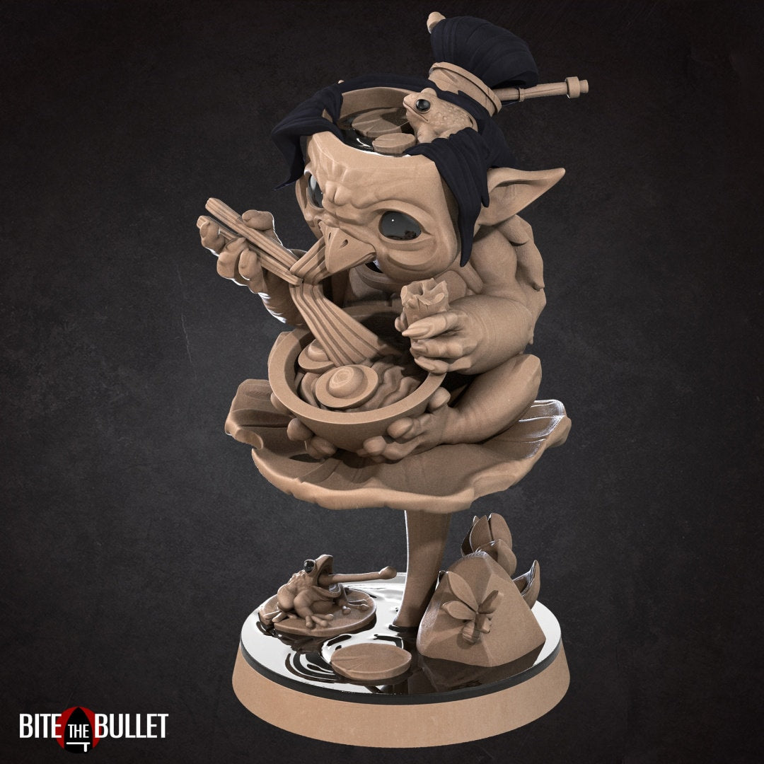 Kappa (anthropomorphic turtle) sitting on a lily pad, eating ramen. Resin miniature by Bite the Bullet.