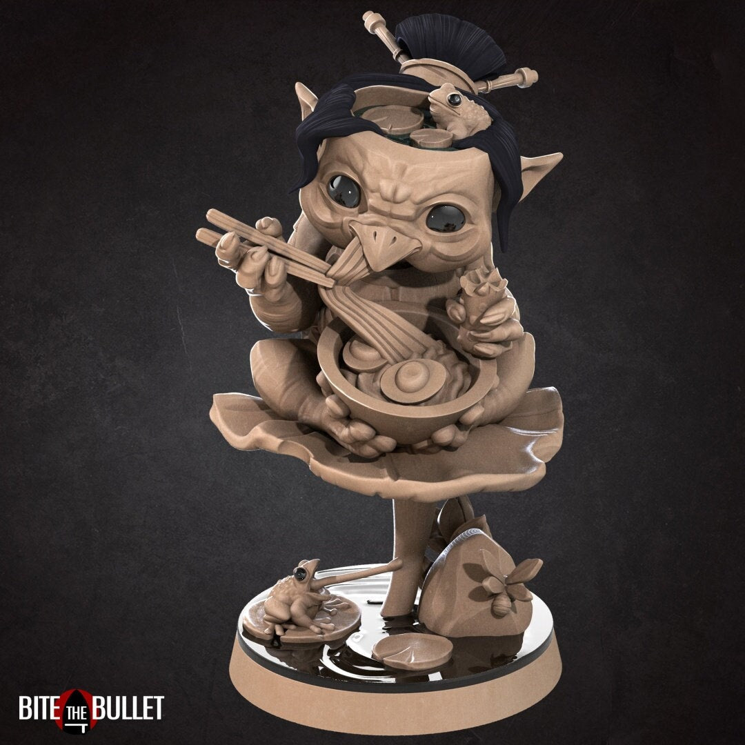 Kappa (anthropomorphic turtle) sitting on a lily pad, eating ramen. Resin miniature by Bite the Bullet.