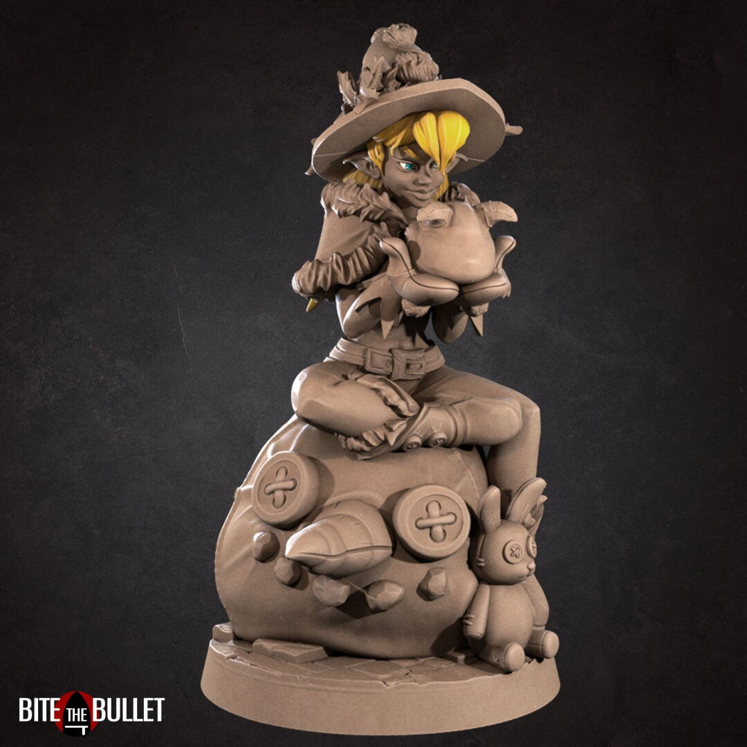 Christmas elf girl sitting on a toy snowman head, holding a toy that's sticking its tongue out at her. Resin miniature by Bite the Bullet.