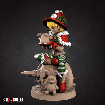 Christmas elf girl sitting on a toy snowman head, holding a toy that's sticking its tongue out at her. Resin miniature by Bite the Bullet.