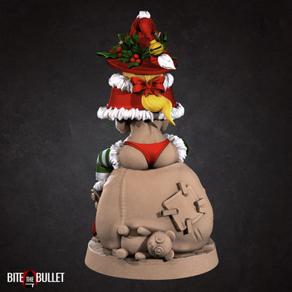 Christmas elf girl with a bare midriff and bikini bottom sitting on a toy snowman head, holding a toy that's sticking its tongue out at her. Resin miniature by Bite the Bullet.