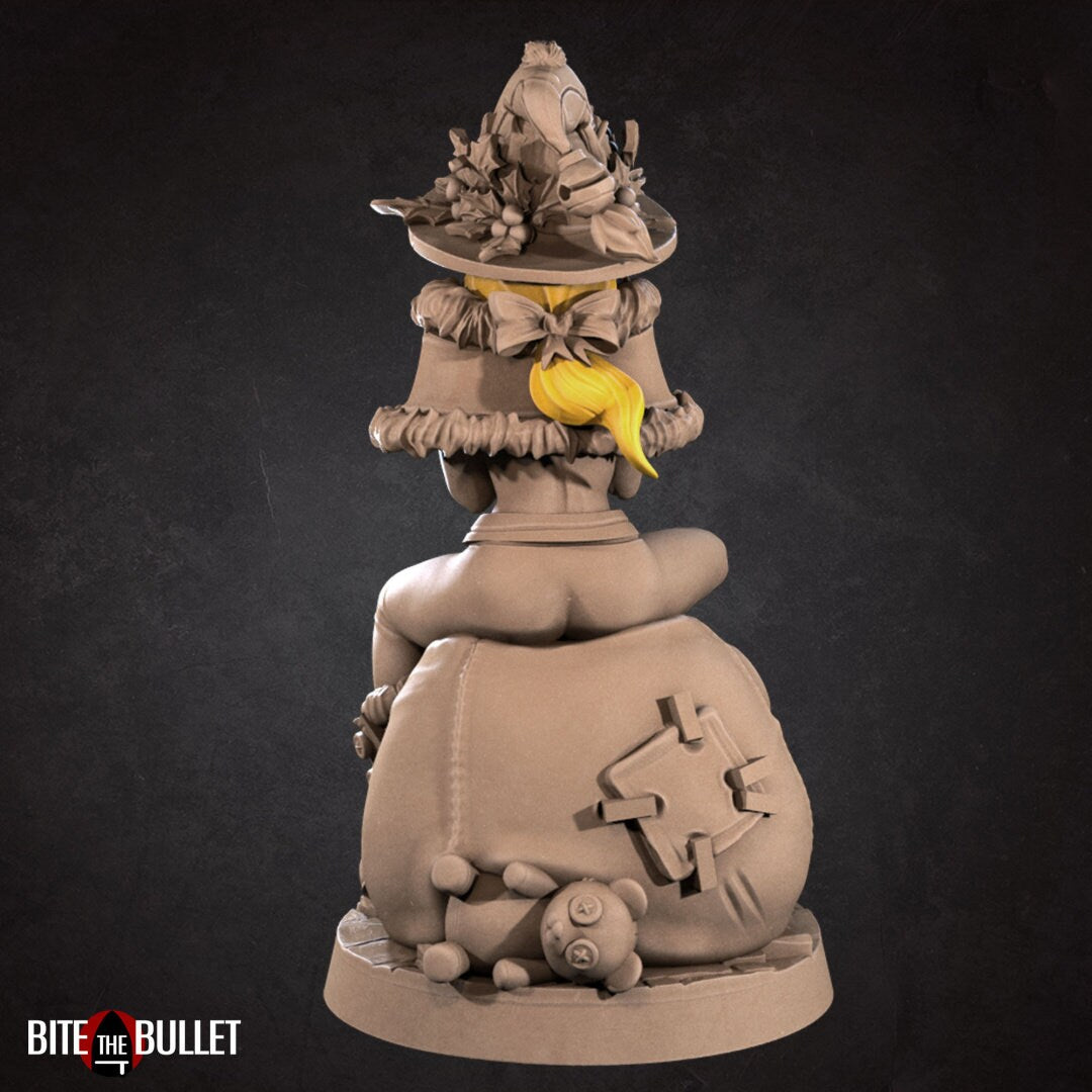 Christmas elf girl sitting on a toy snowman head, holding a toy that's sticking its tongue out at her. Resin miniature by Bite the Bullet.